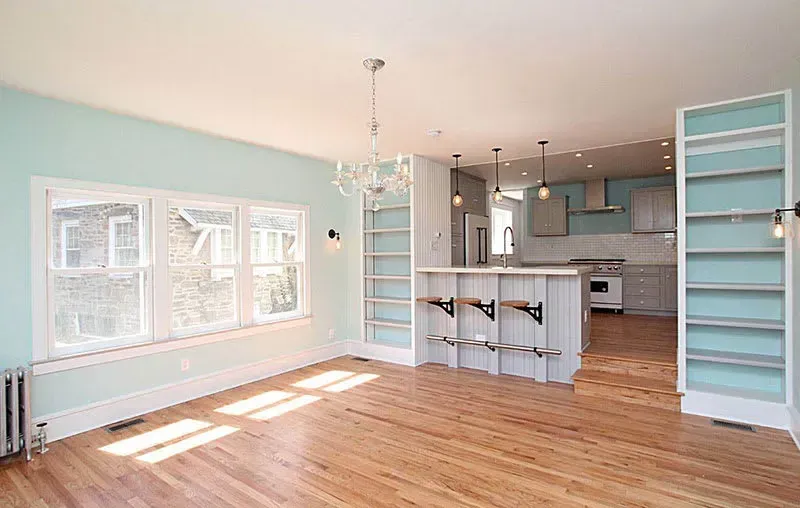 Light-filled open-plan kitchen and dining room with wood floors, light blue walls, and a kitchen island.