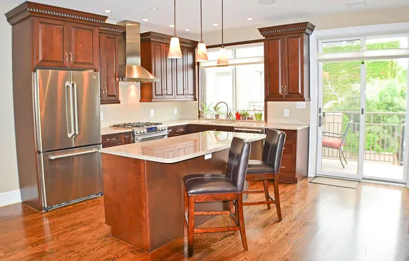 Kitchen with dark wood cabinets, stainless steel appliances, and an island with two bar stools.