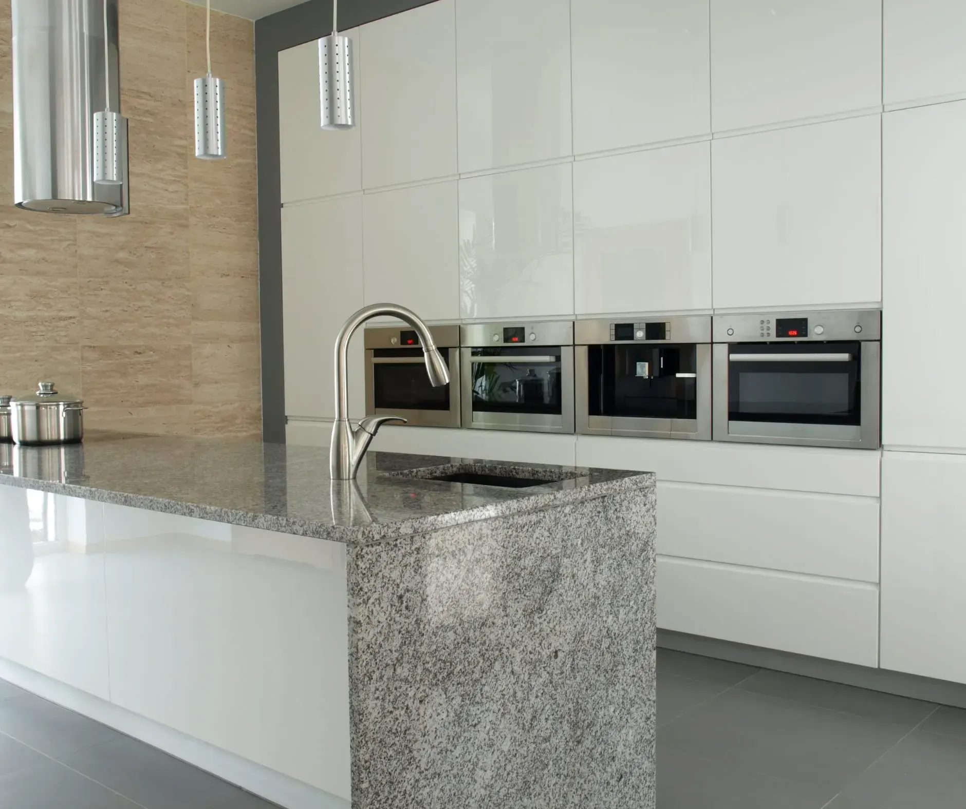 Modern white kitchen with granite island, stainless steel appliances, and pendant lights.