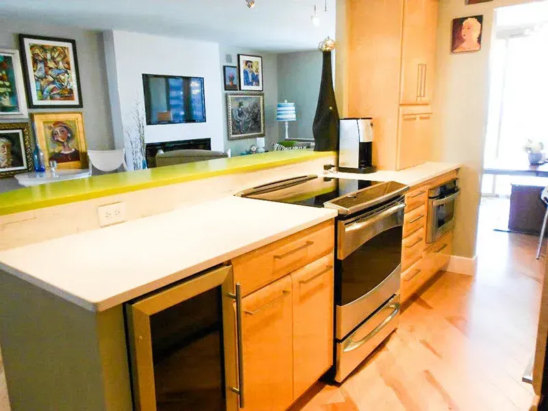 Kitchen with light wood cabinets, stainless steel appliances, and countertop separating the kitchen from the living room.