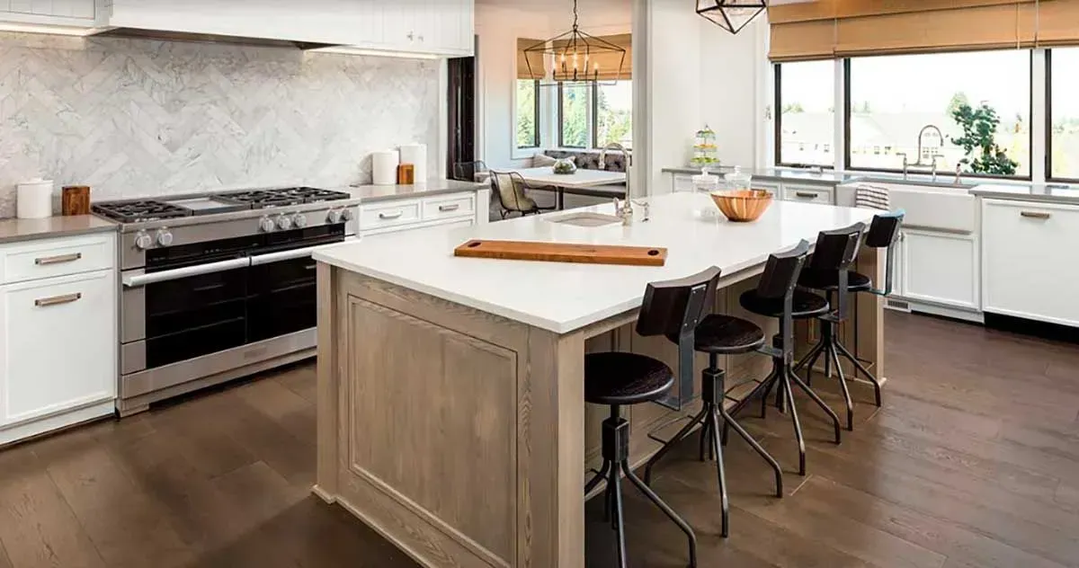 Modern kitchen with a large island, stainless steel appliances, and dark wooden floors.