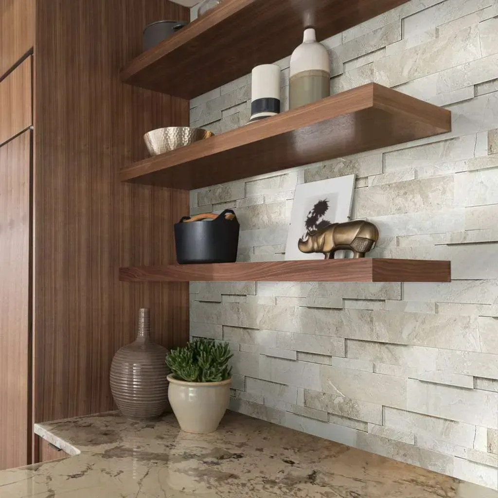 Floating shelves with décor against a stone-tiled wall in a kitchen, featuring a countertop, plants, and pottery.