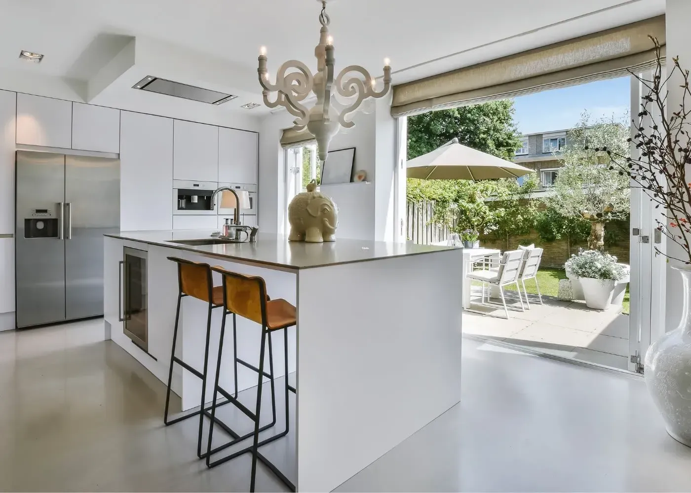 L-shaped kitchen with wood cabinets, white countertops, and a high ceiling with large windows.