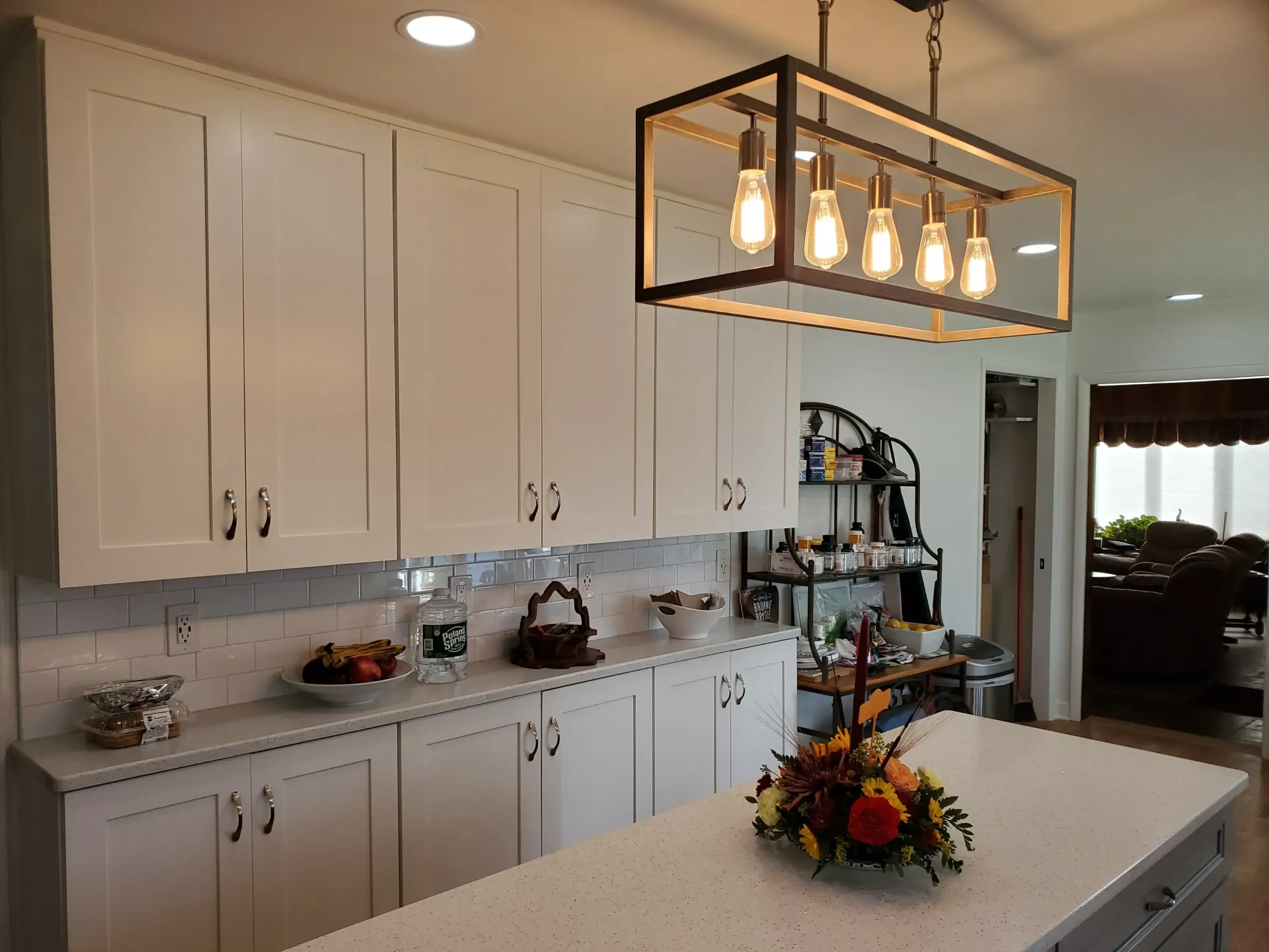 Kitchen with white cabinets, island, and a rectangular light fixture with Edison bulbs.