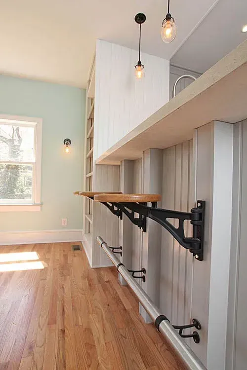 A small breakfast bar with a wooden top and cast iron brackets mounted on a wall.