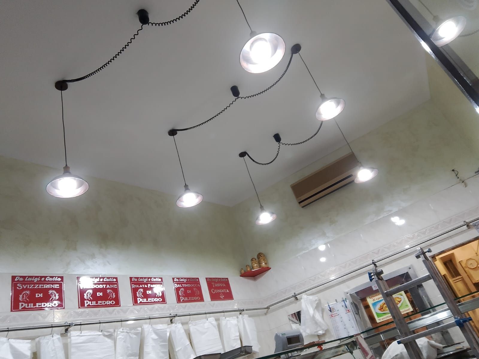 Plafoniere in un ambiente commerciale, con soffitto bianco e cablaggio nero in alto.