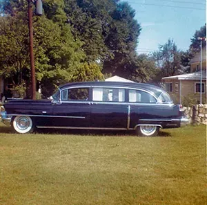 Navy blue older version of hearse on grass, Mynatt Funeral Home, Inc.