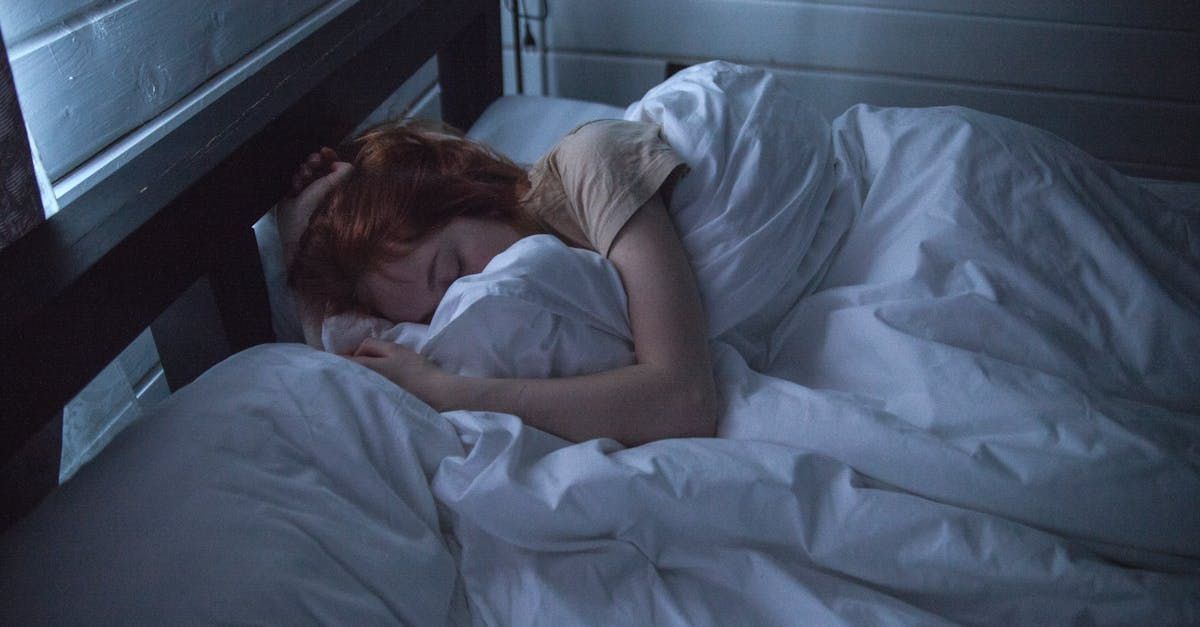 A woman is sleeping in a bed with white sheets and pillows.