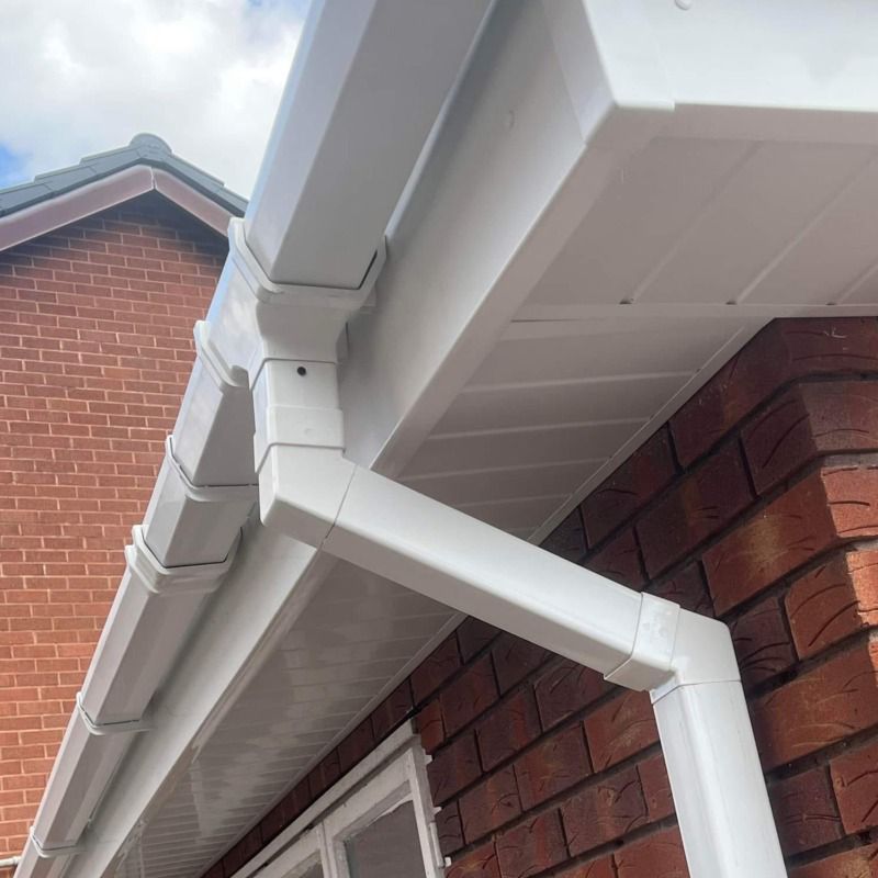 White gutters and soffit on a brick building under a cloudy sky.