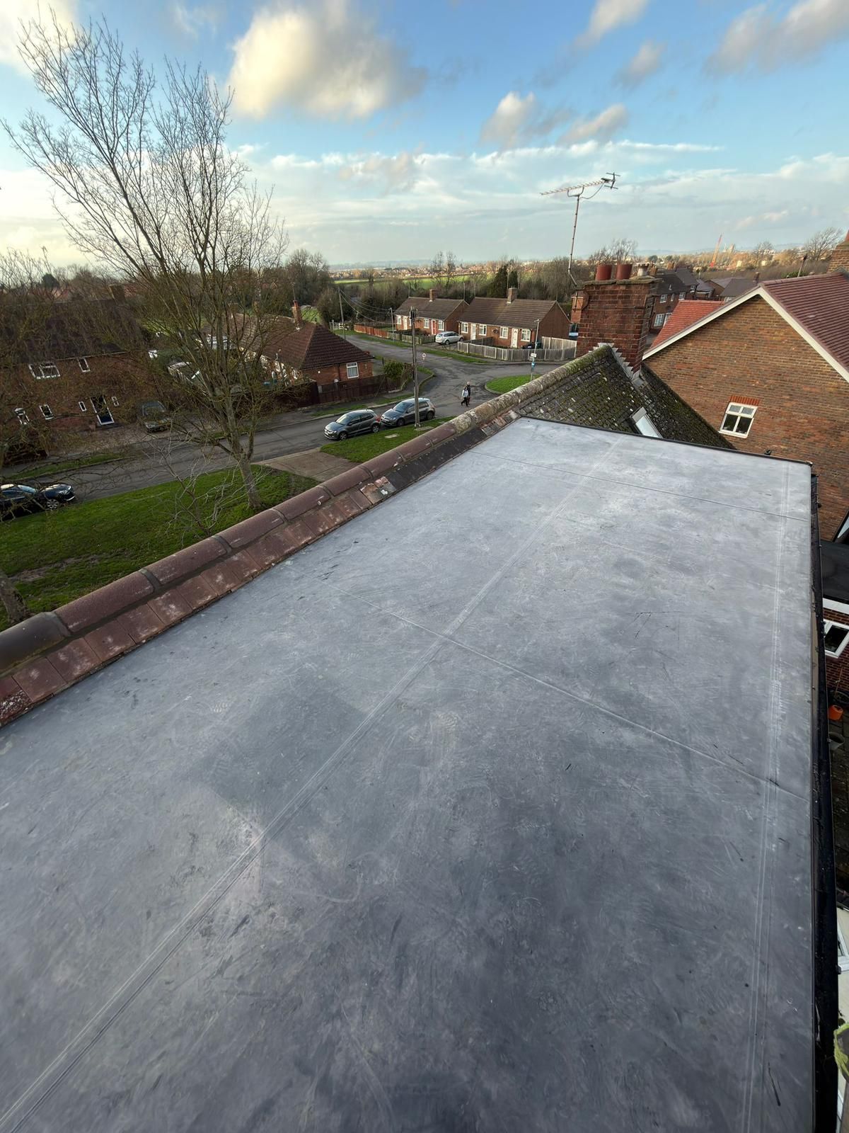 View from a flat roof overlooking a residential area on a cloudy day.