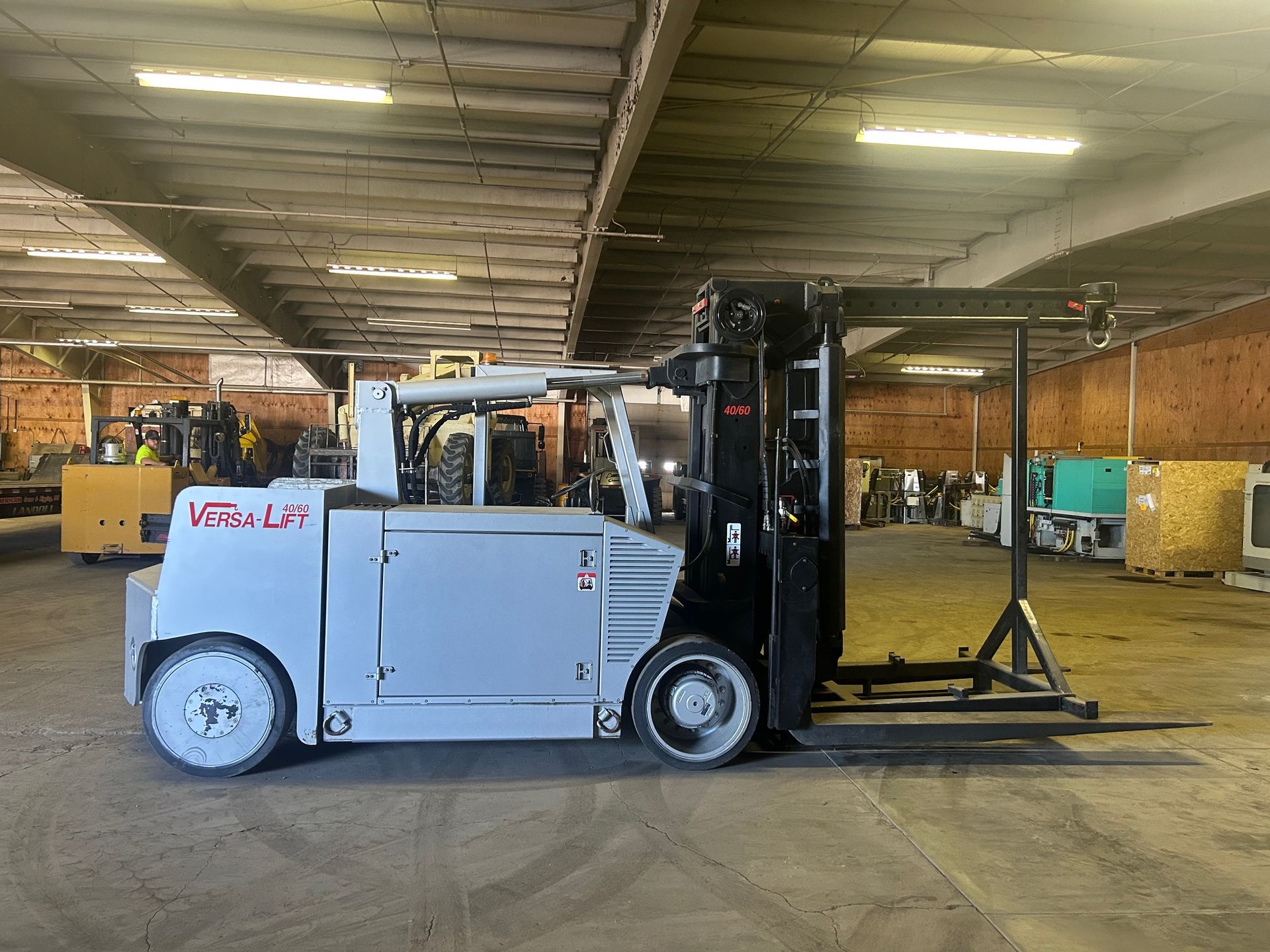 Gray Versa-Lift forklift in a warehouse. It has large wheels and a black lifting mechanism.