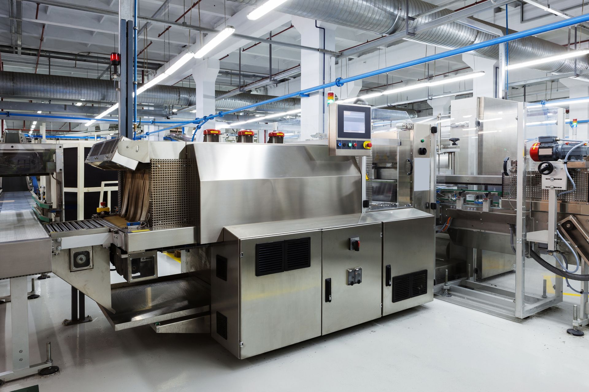 Industrial machine in a factory setting with a control panel and conveyor belt.