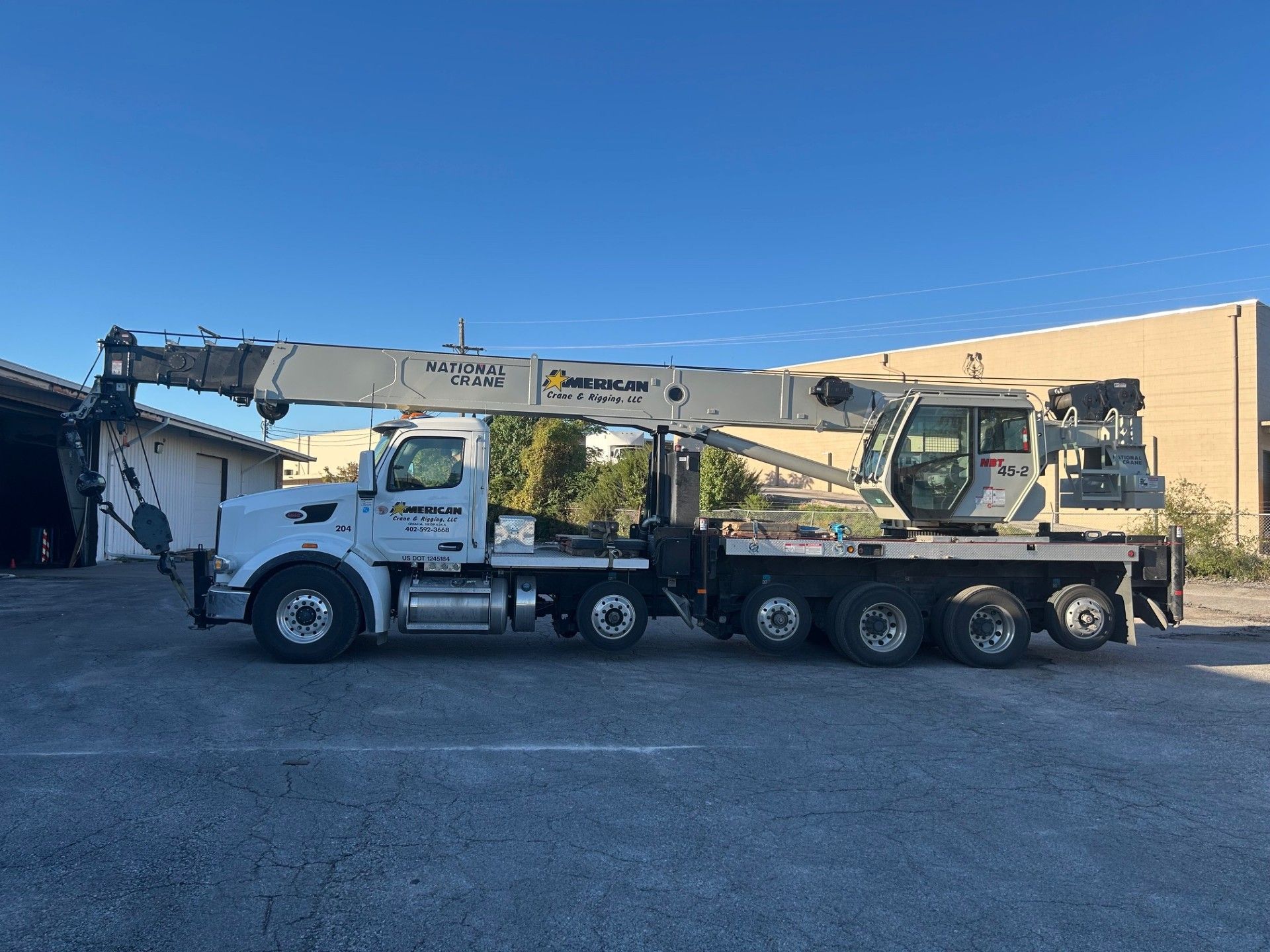 A large yellow crane on wheels in a field under a blue sky with light clouds.