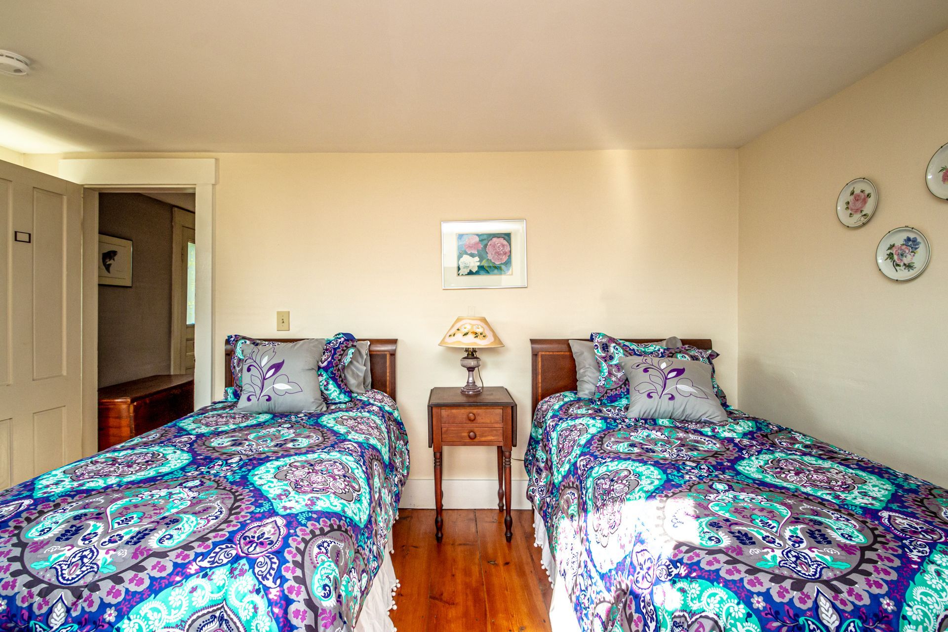 Two twin beds with patterned bedding and small nightstand in a bedroom.