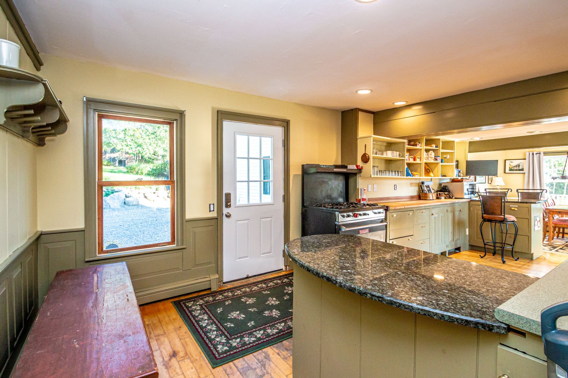 Kitchen with granite countertops, wooden floors, and a view of the outside.