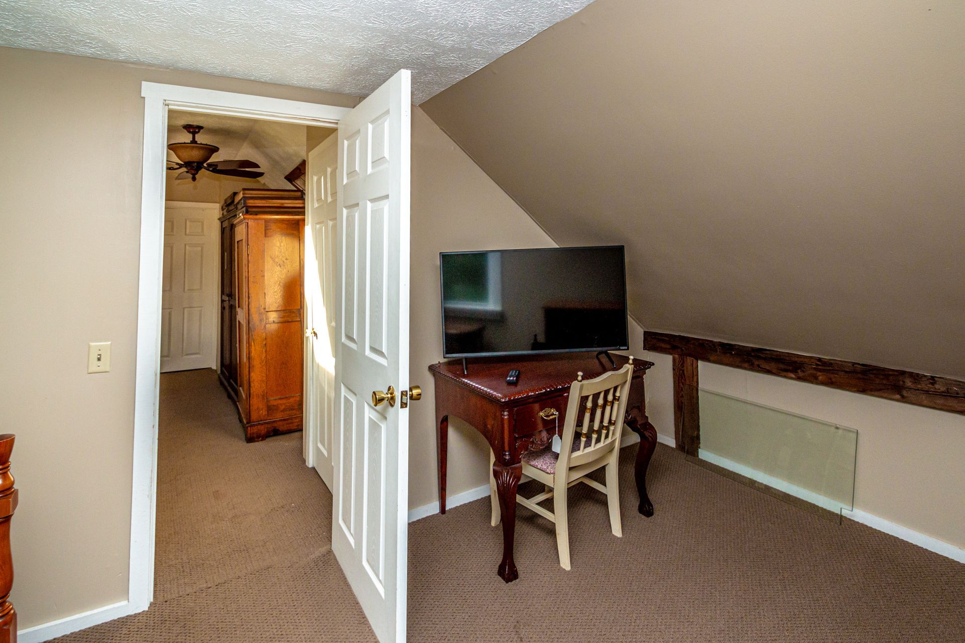 Interior room with open doorway, desk with TV, and carpeted floor.