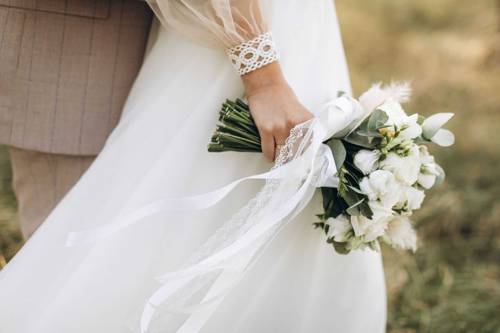 A bride in a white dress is holding a bouquet of white flowers.