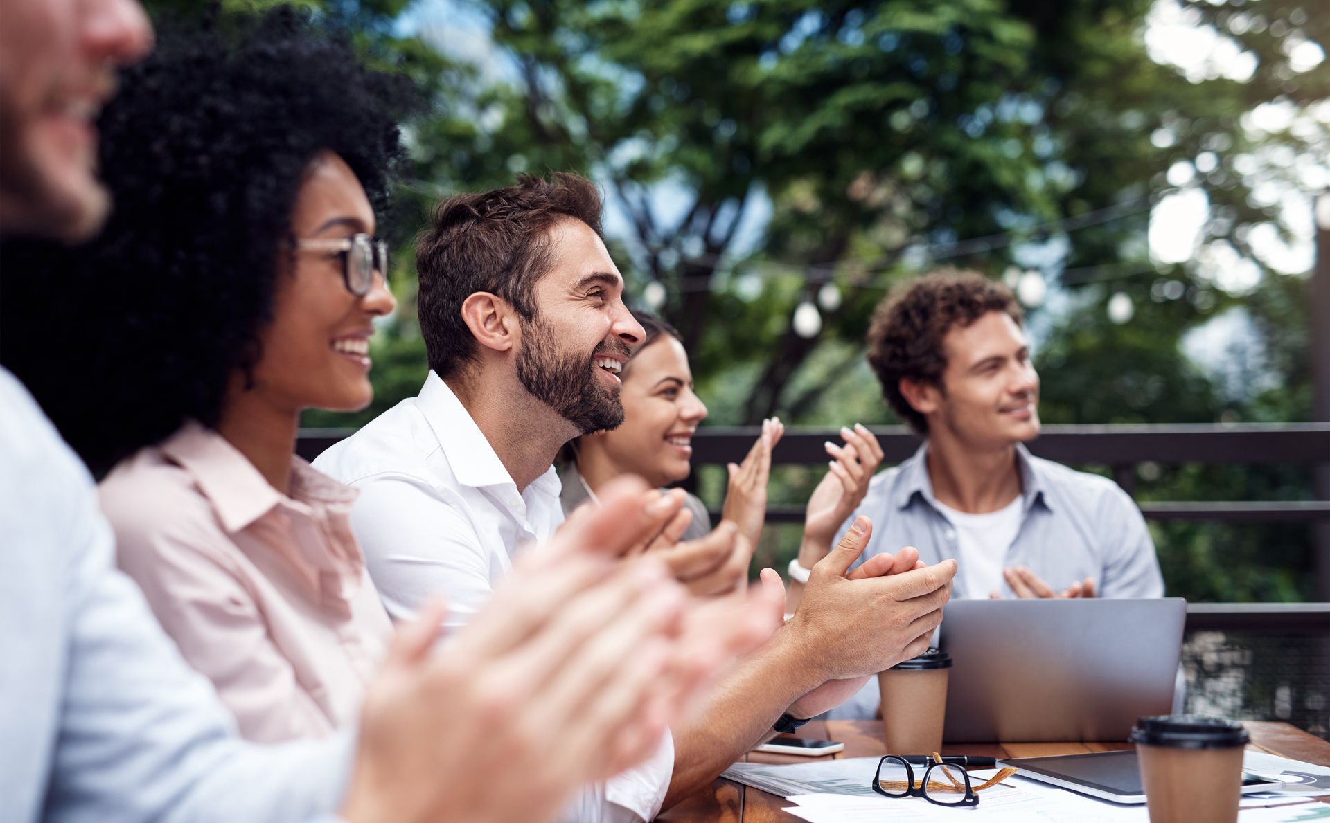 A group of people are sitting at a table clapping their hands.