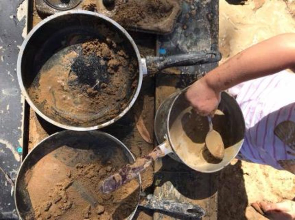boy taking a spoonful of liquid soil