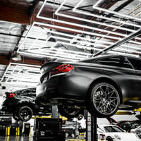 Two black cars lifted on hydraulic lifts in a modern auto repair shop