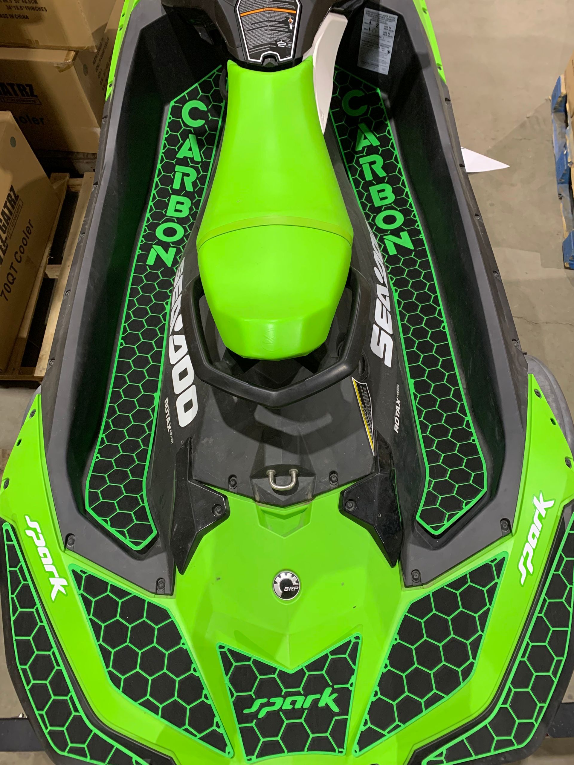 A green and black jet ski is sitting in a warehouse.