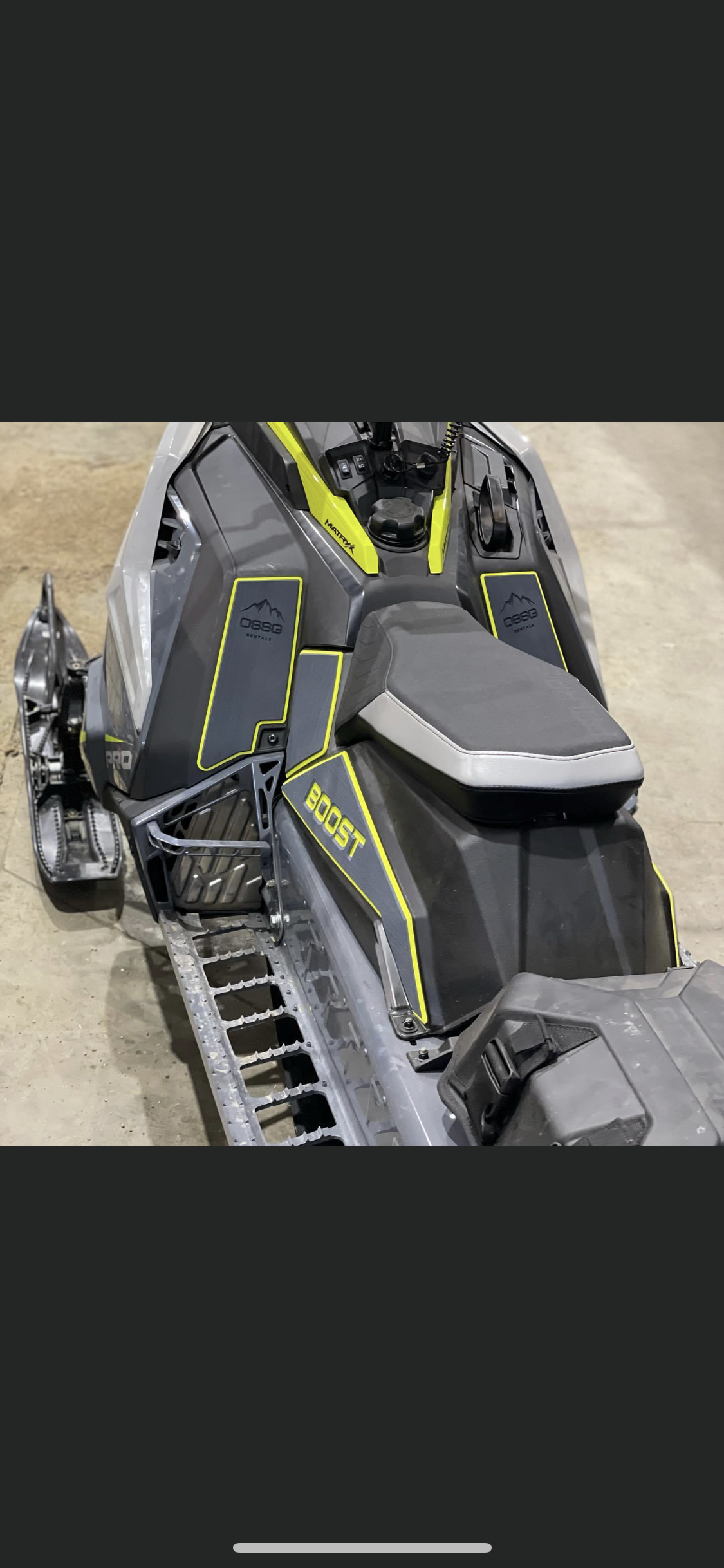 A snowmobile is parked on the ground in a garage.