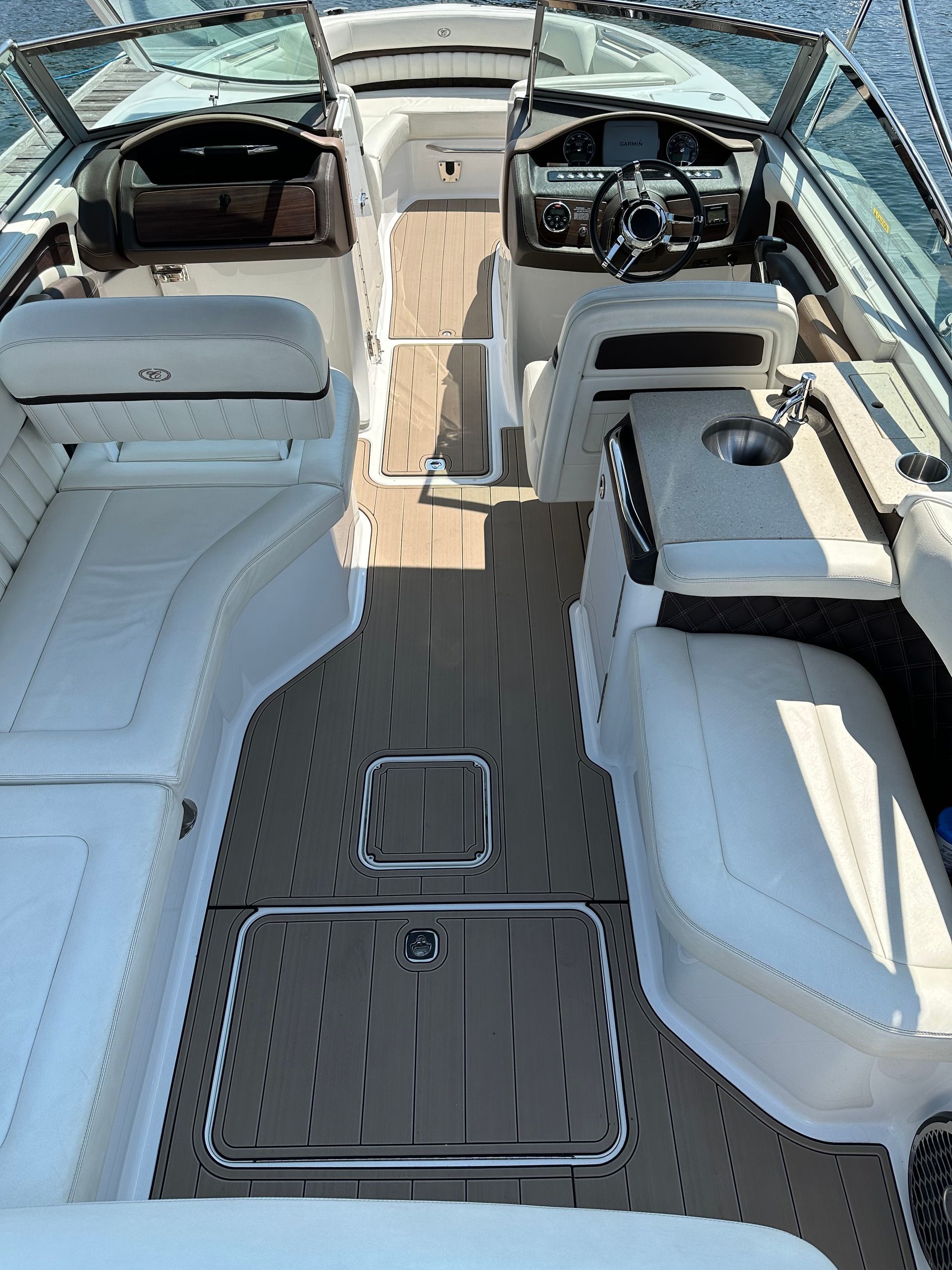 The inside of a boat with a wooden deck and a steering wheel.