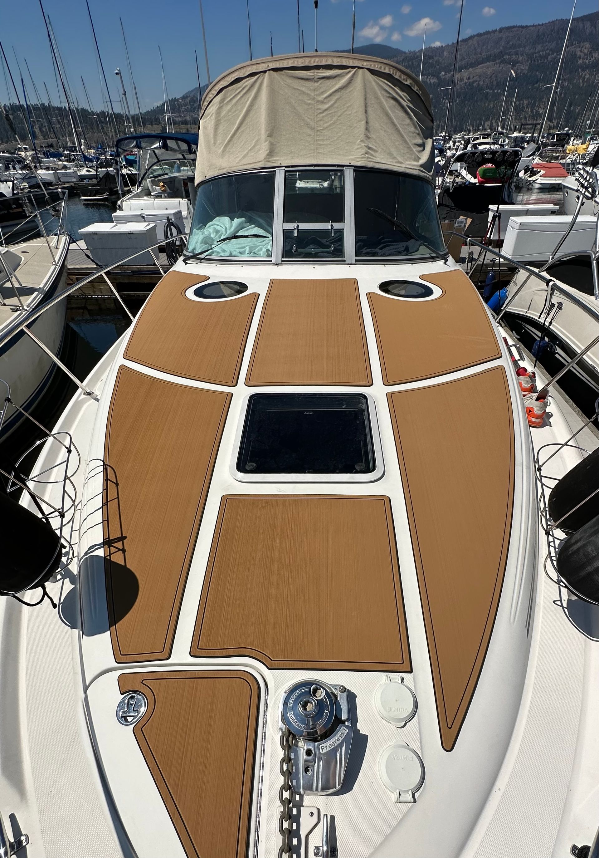 A boat with a wooden deck is docked in a marina.