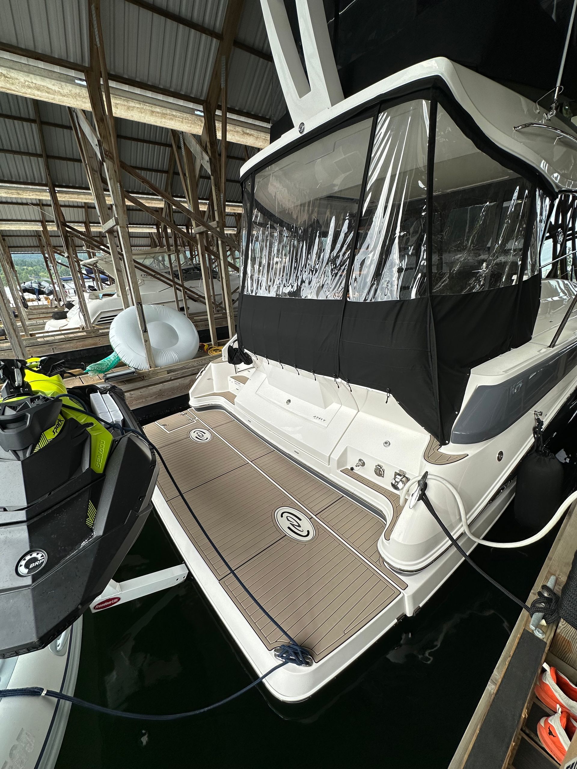 A boat is docked in a warehouse next to a jet ski.