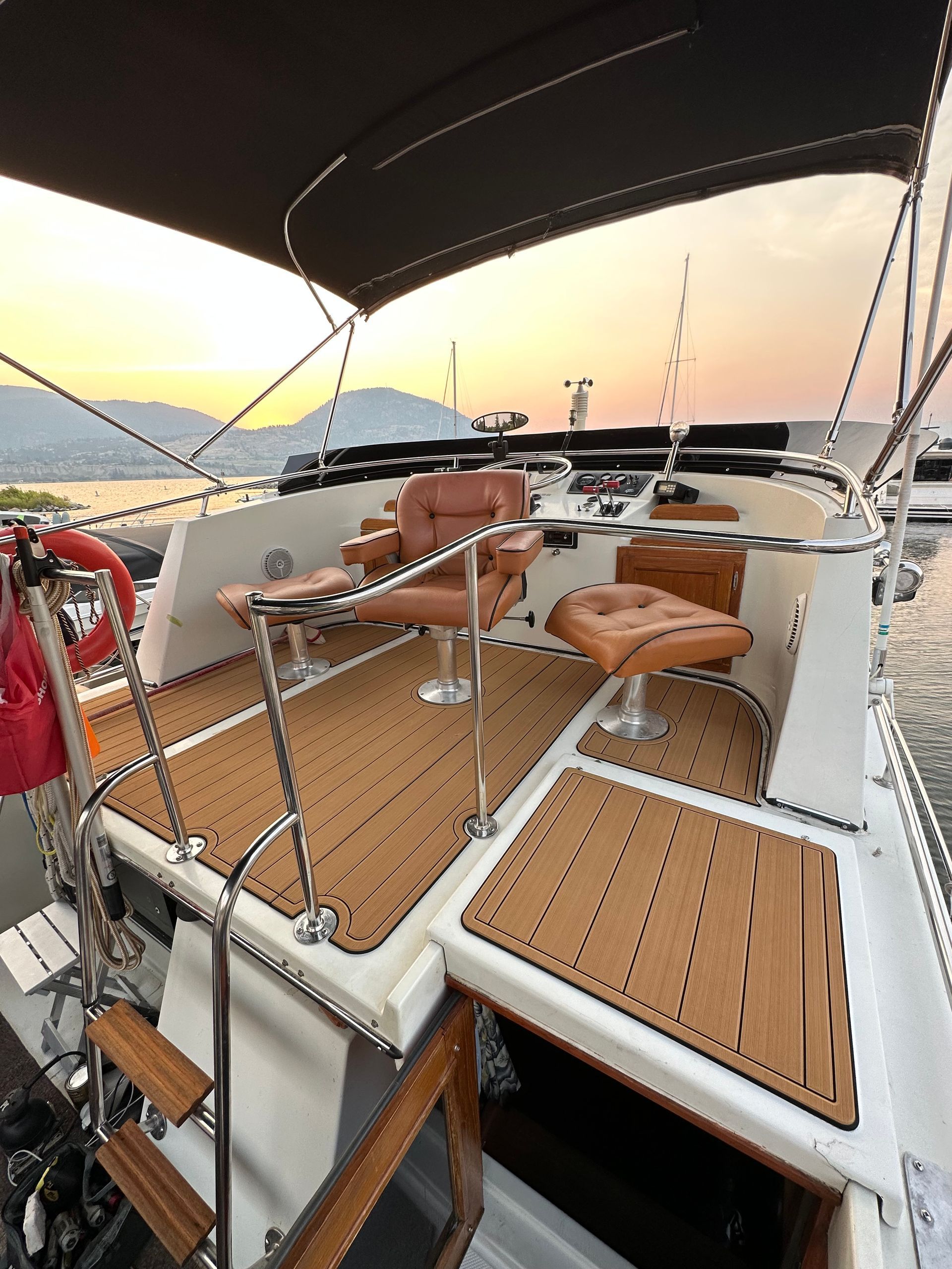 A boat with a wooden deck and chairs on it is in the water.