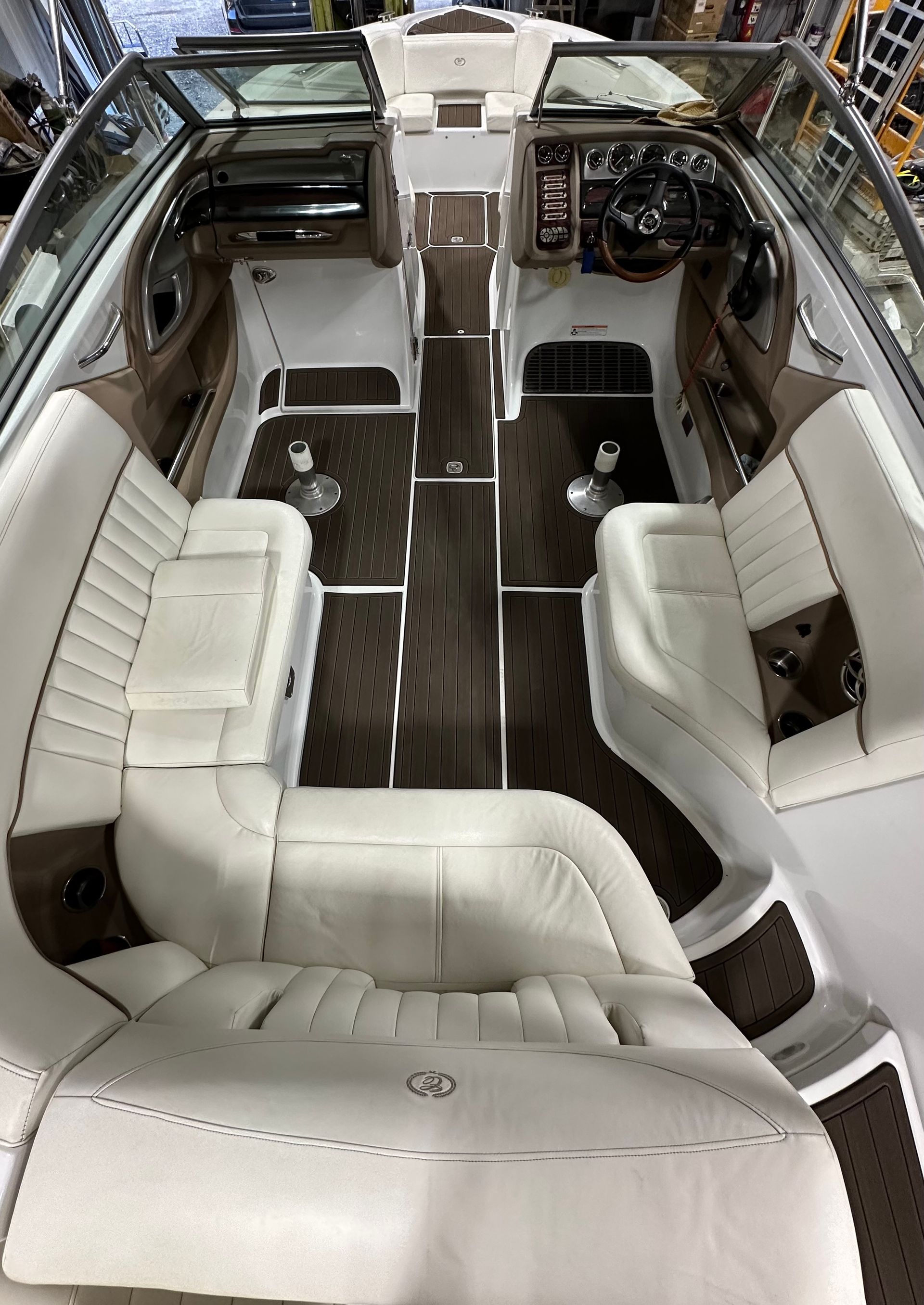 The inside of a boat with white seats and a wooden floor.