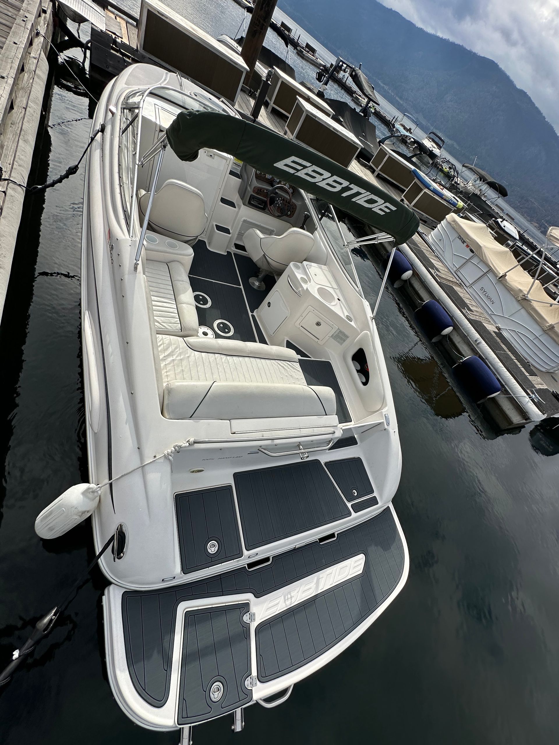A white boat is docked at a dock in the water.
