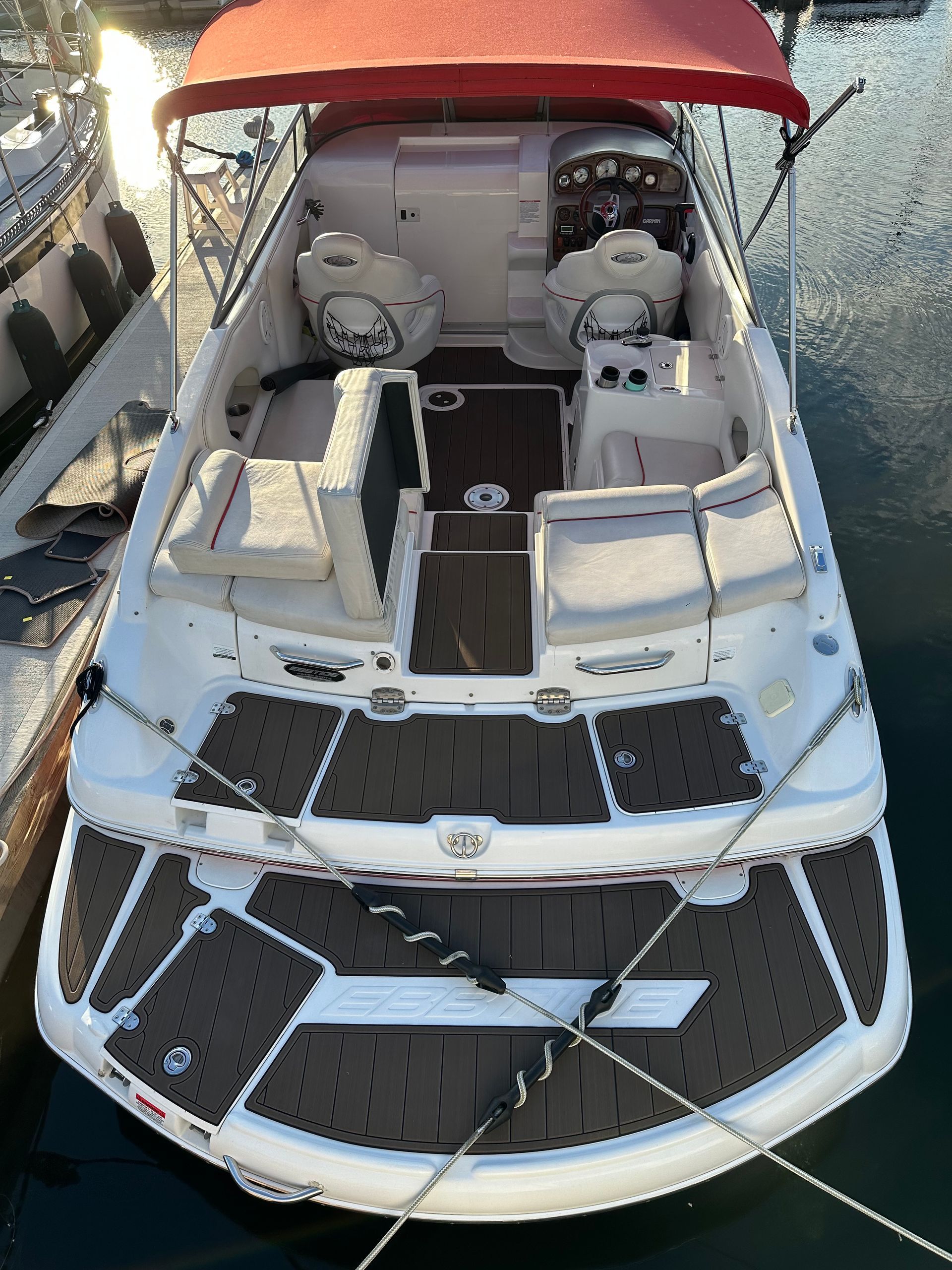A white boat with a red canopy is docked in the water.