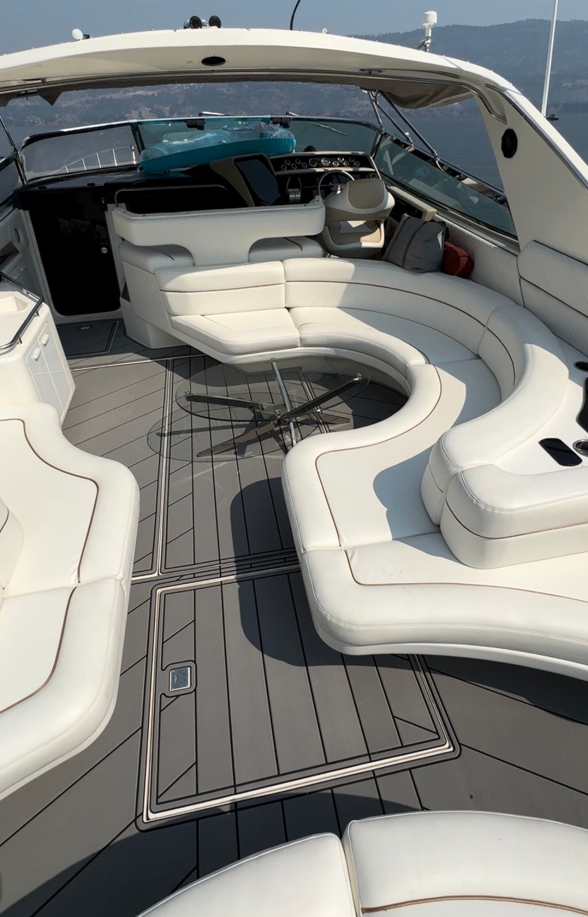 The inside of a boat with white cushions and a table.