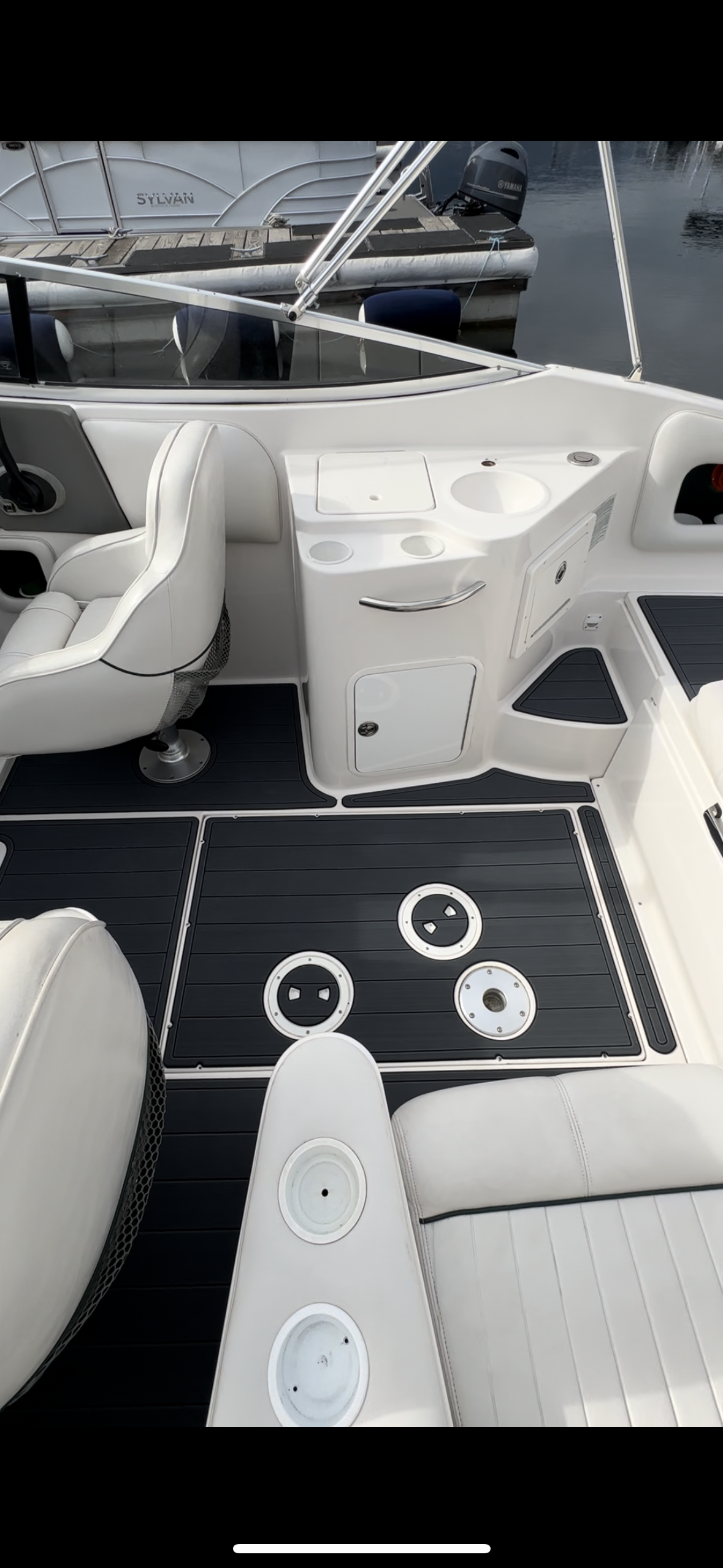 The inside of a boat with a black and white mat on the deck.