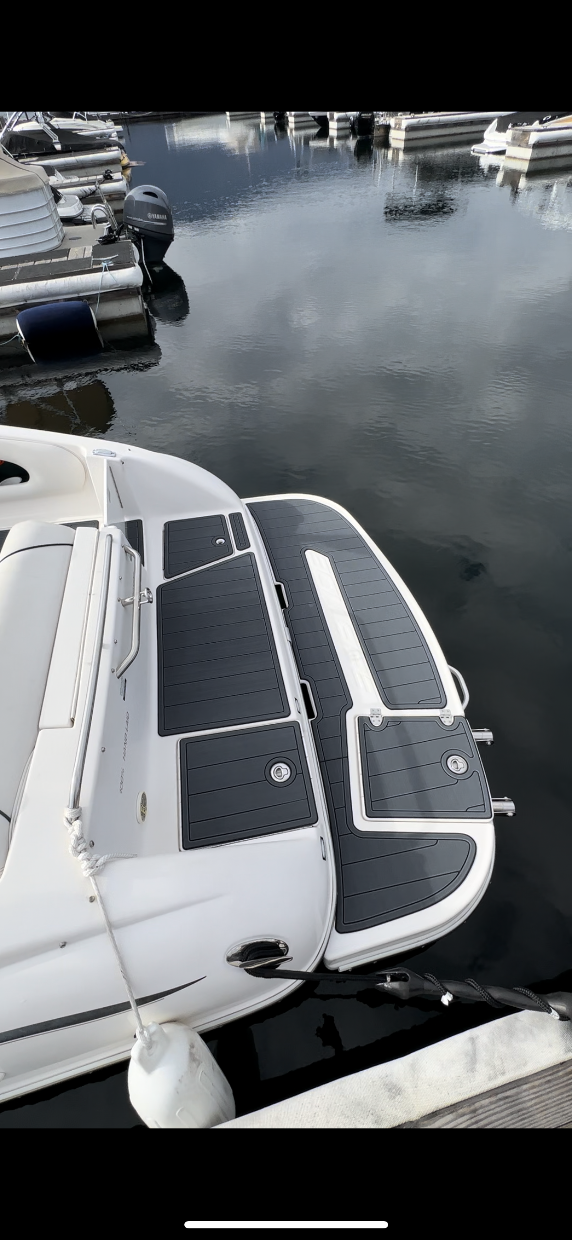 A white boat is docked at a dock in the water.
