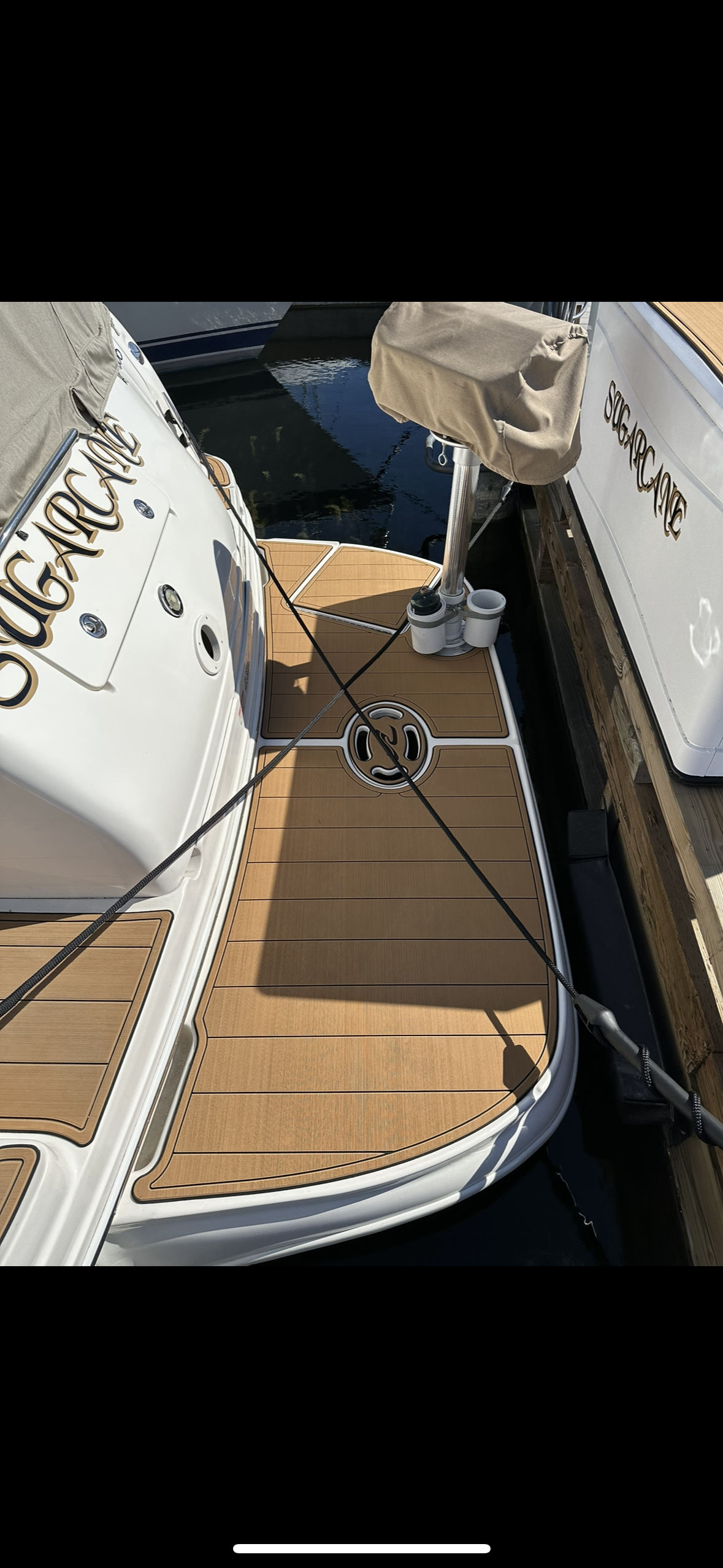 A white boat with a wooden deck is docked in the water.