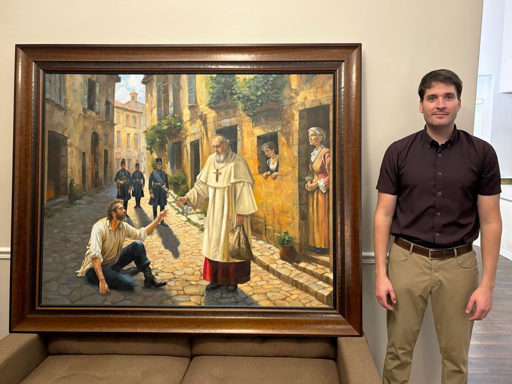 Man standing next to a painting of Les Misérables.