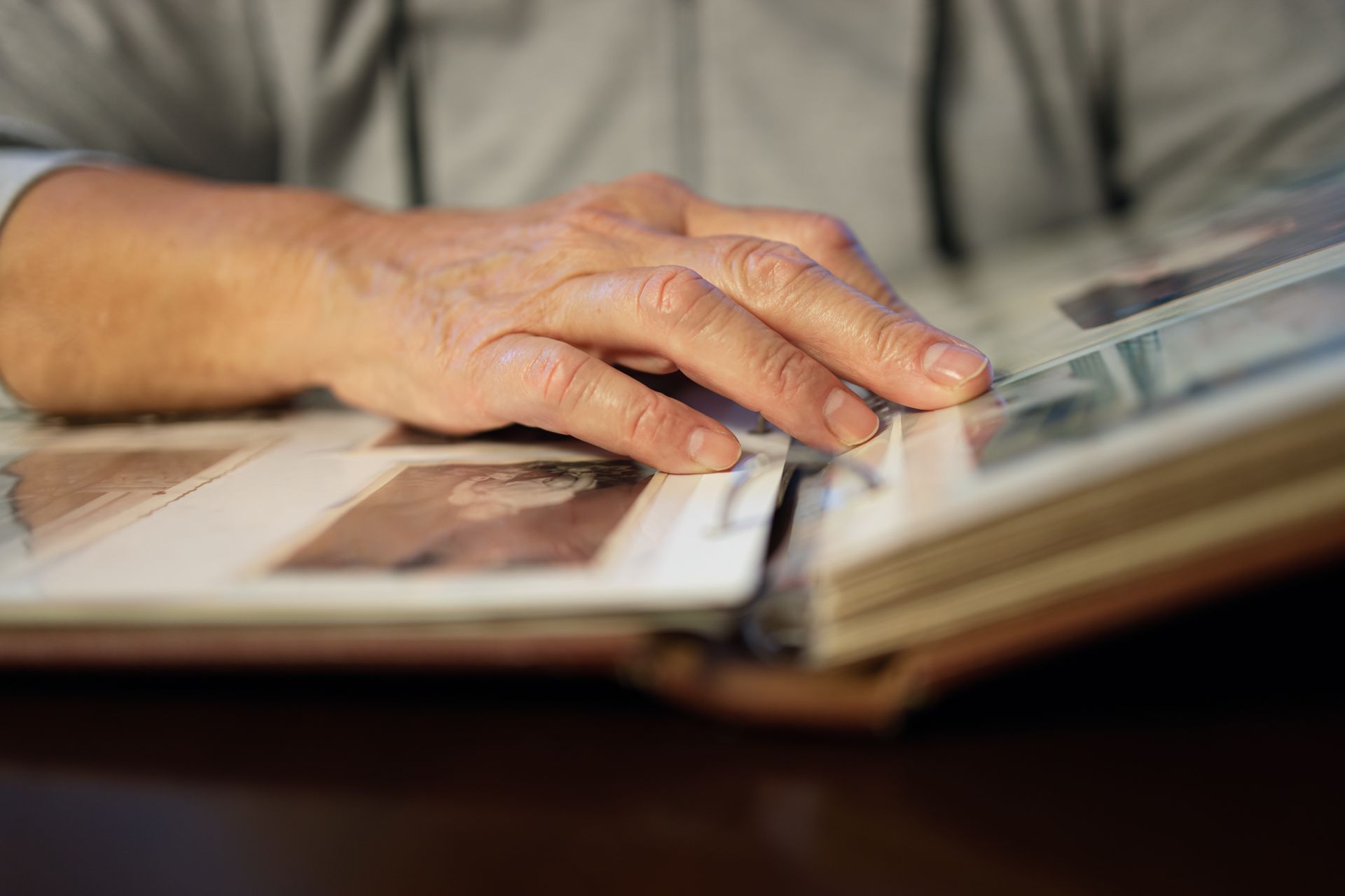 Hand resting on an open photo album, turning a page on a table