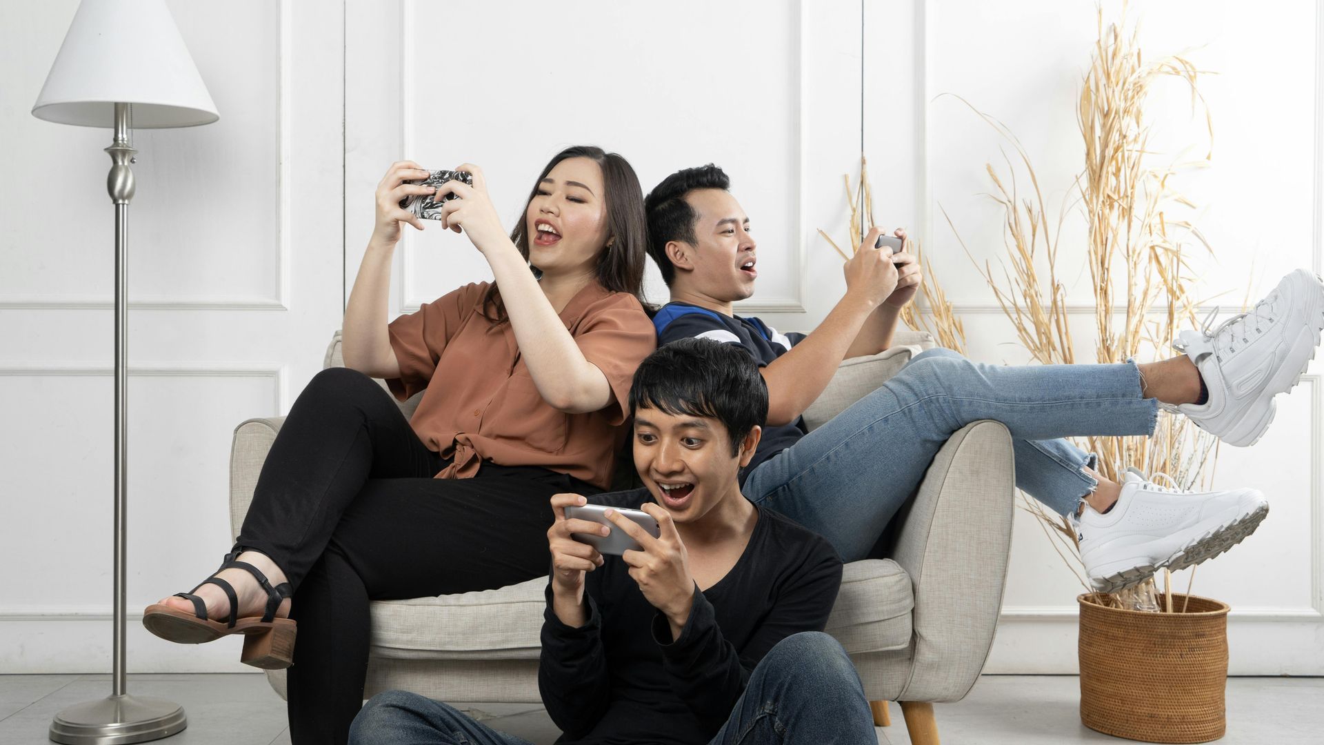 A group of people are sitting on a couch using the Internet.