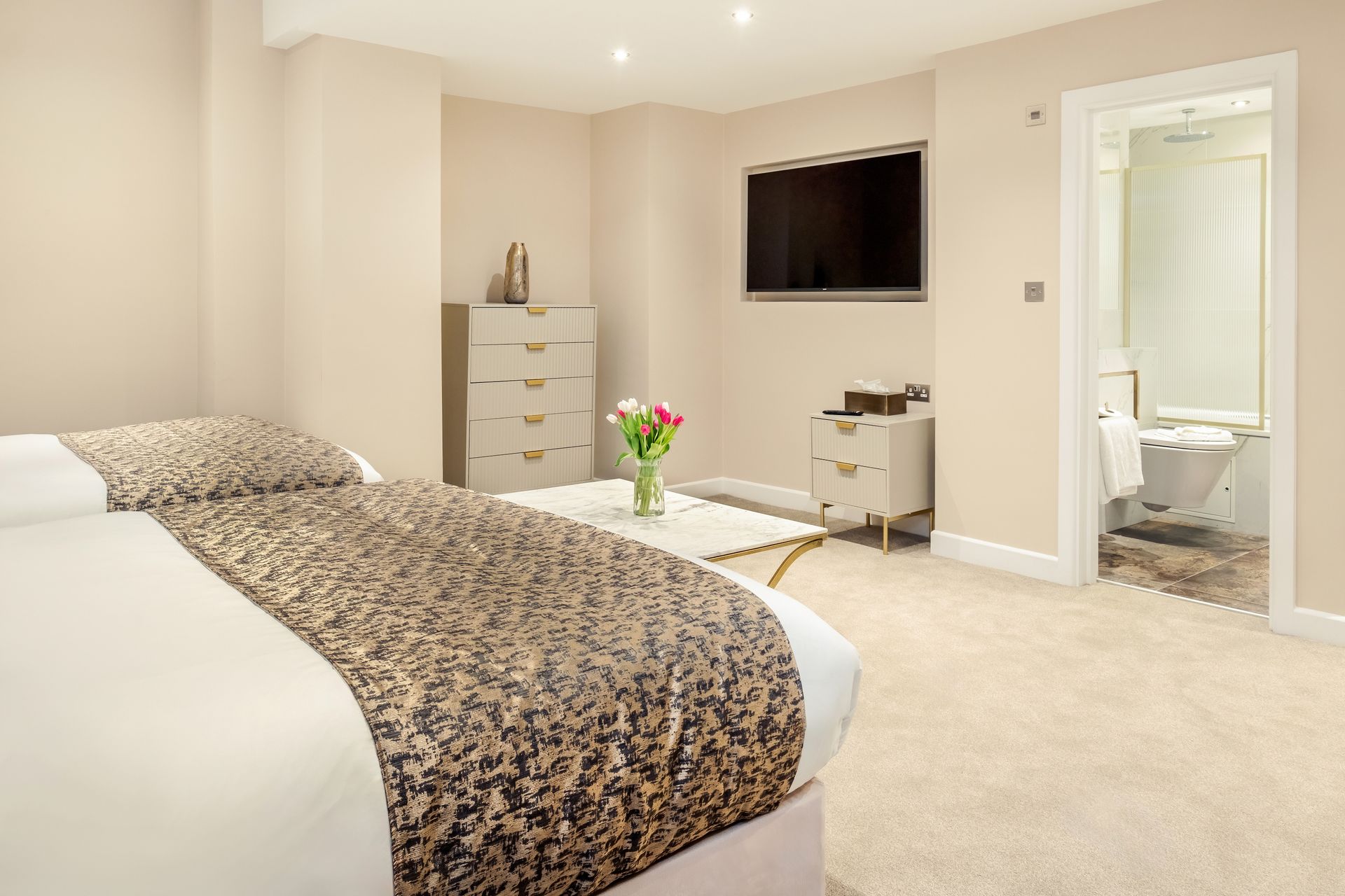 A bedroom with a king size bed , dresser , television and a bathroom.