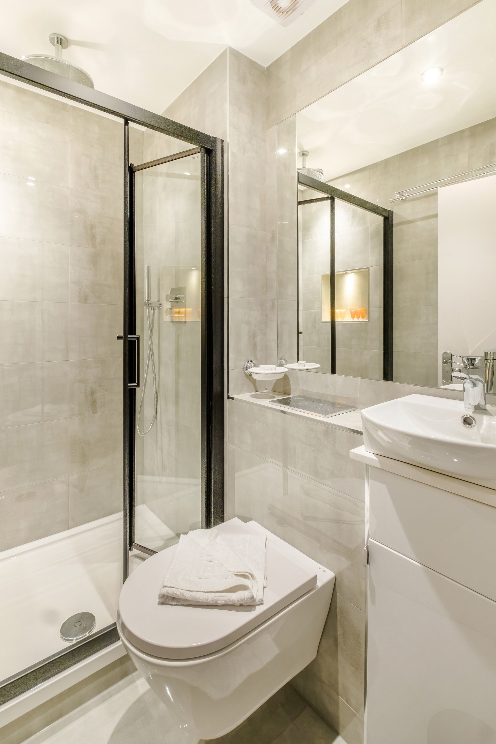 A bathroom with a toilet , sink , shower and mirror.