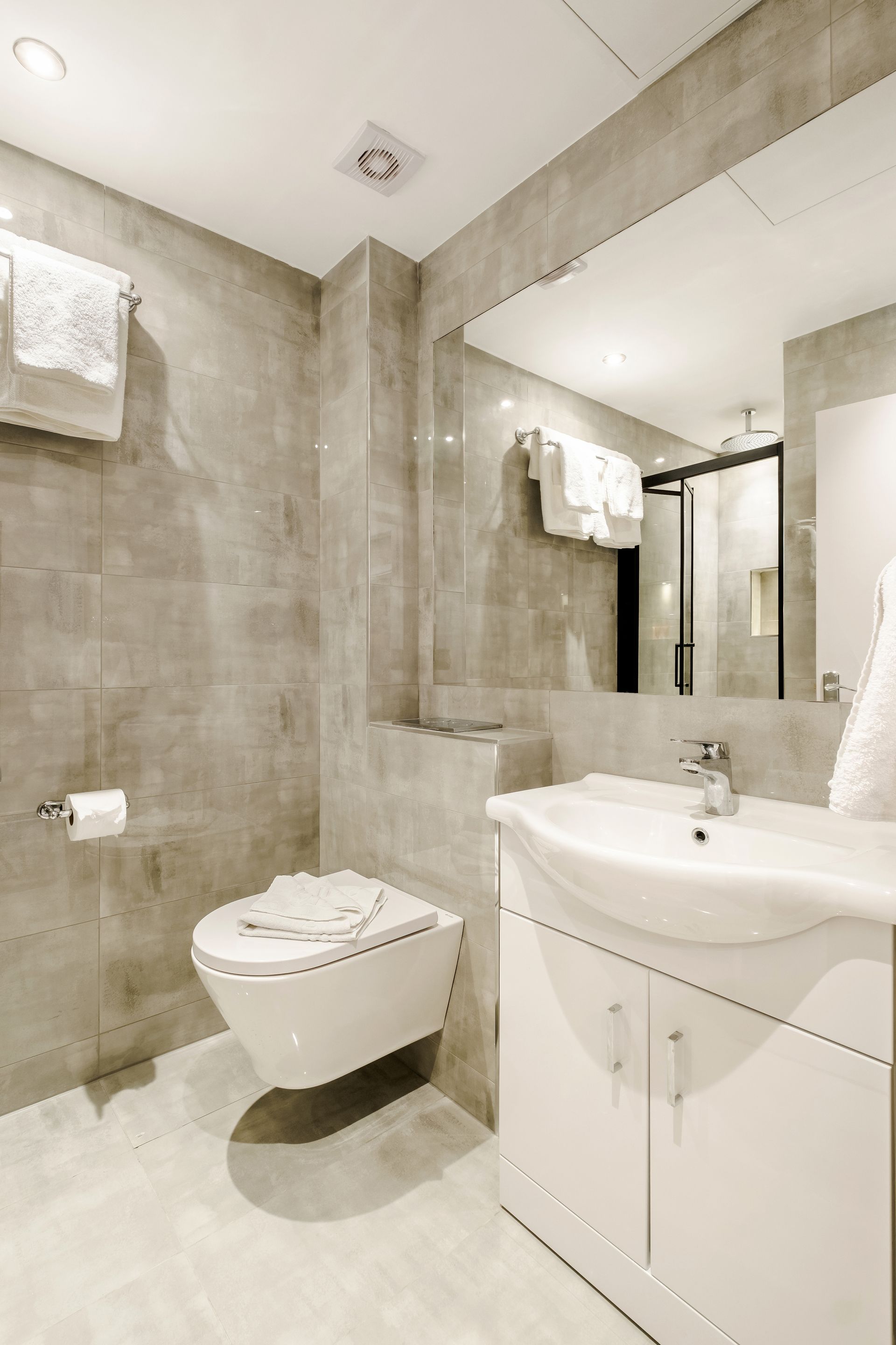 A bathroom with a toilet , sink and mirror.