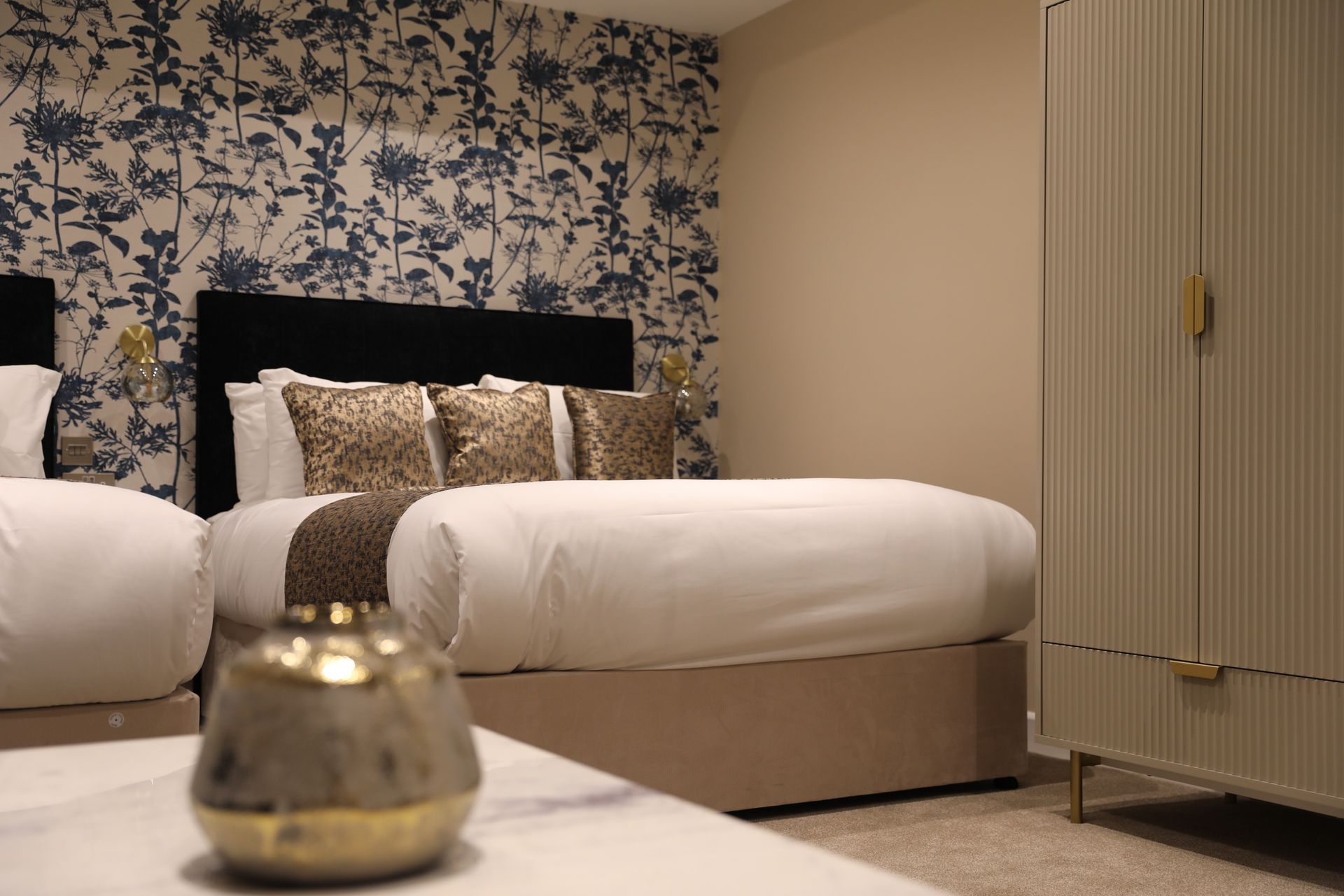 A hotel room with two beds and a vase on the table.