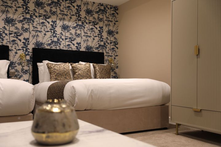 A bedroom with a bed , dresser , and vase of flowers.