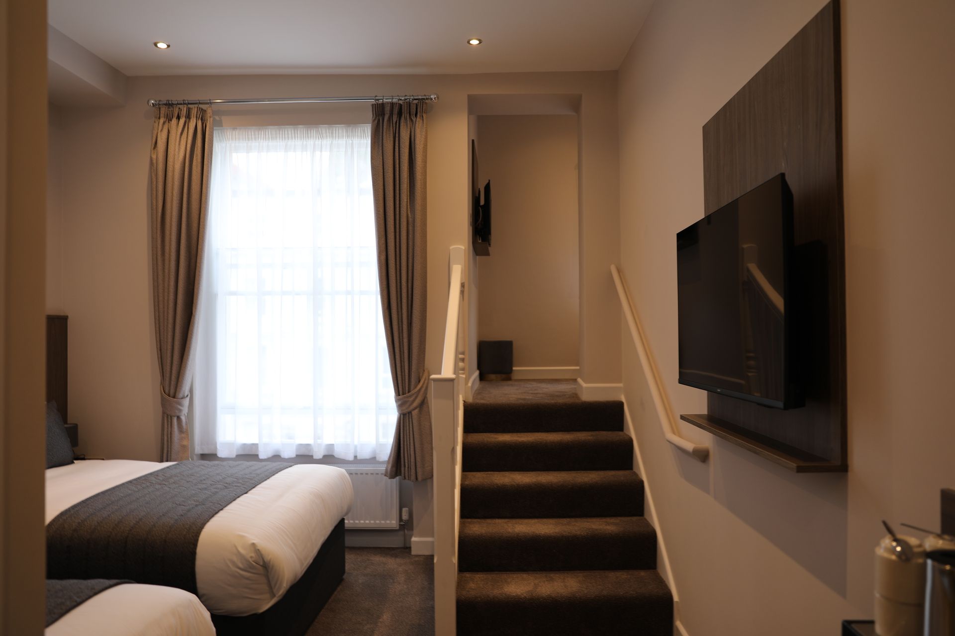 A hotel room with two beds and stairs leading up to the second floor
