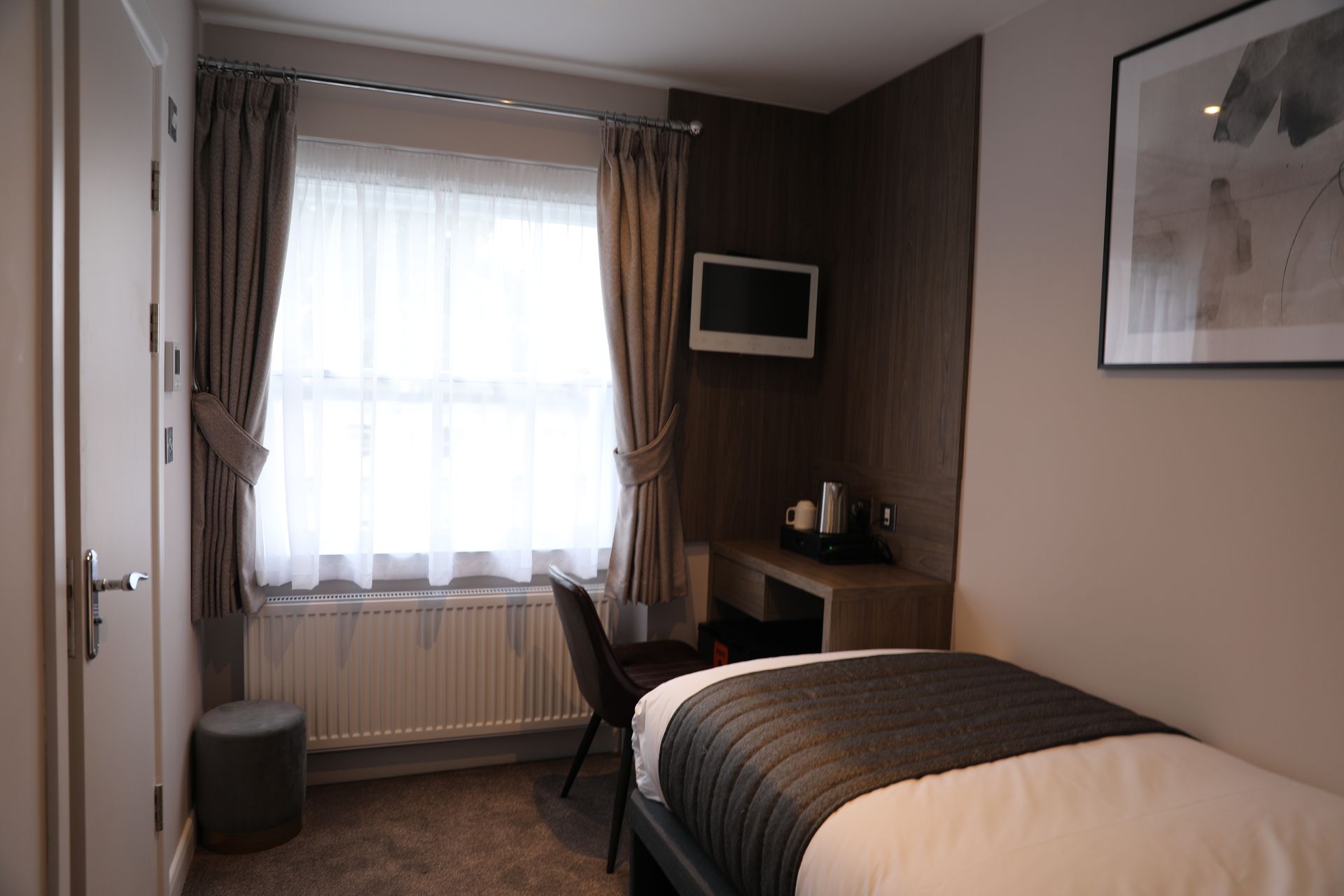 A hotel room with a bed , desk and television