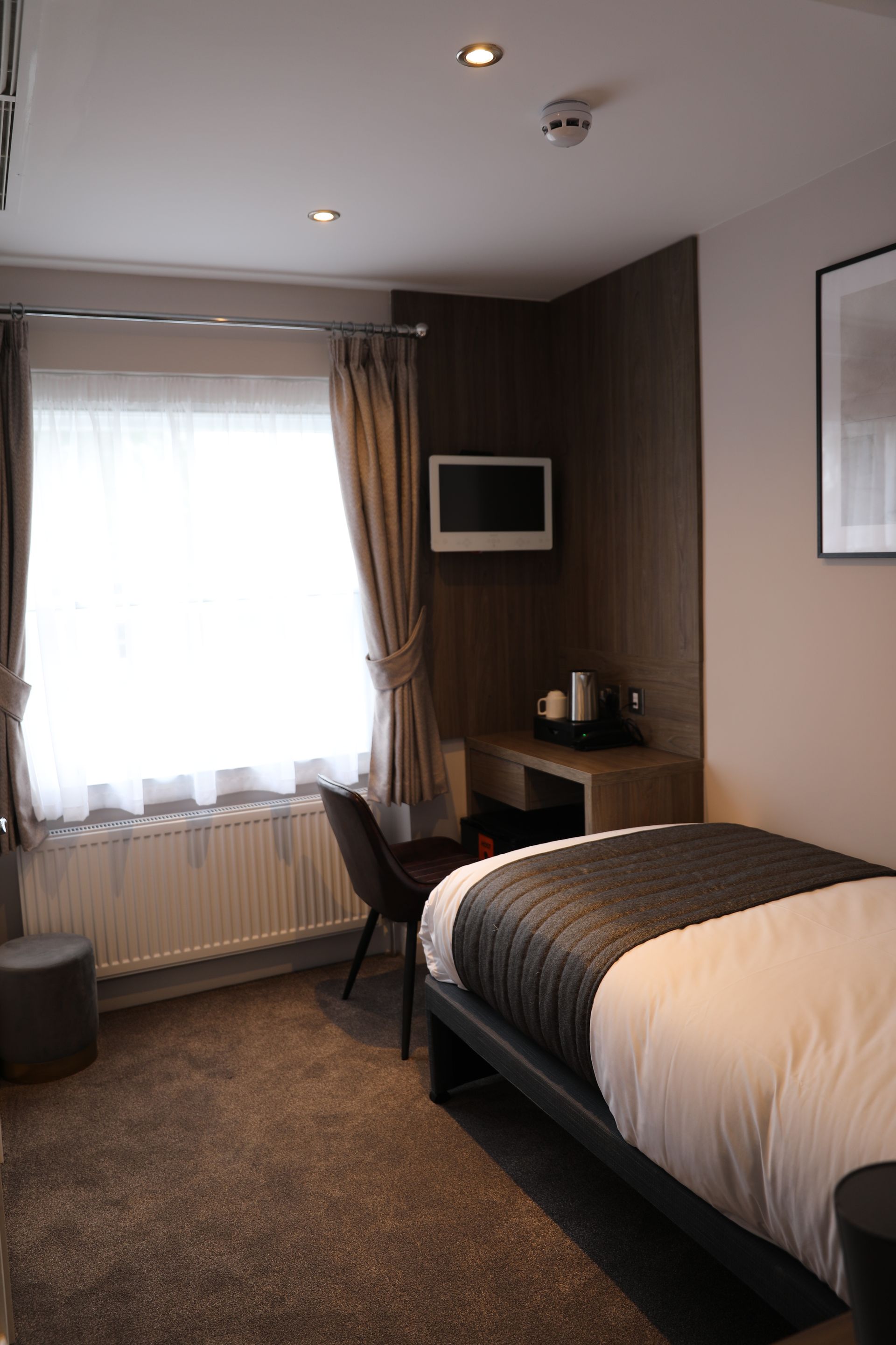 A hotel room with a bed , desk , chair and television.