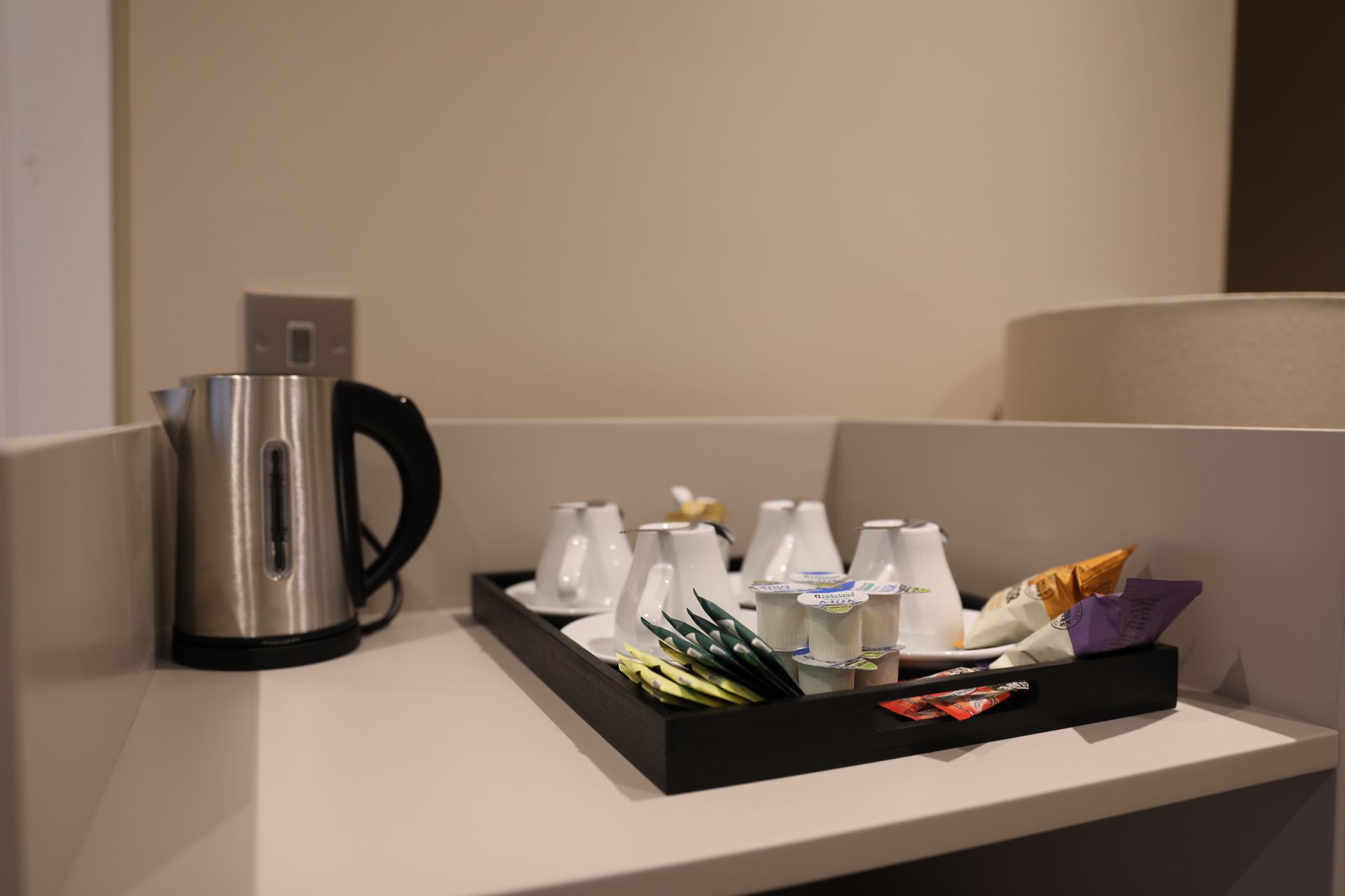 A tray with cups and tea on it is on a counter next to a kettle.