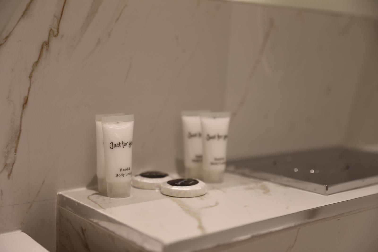 A bathroom counter with bottles of lotion and soap on it.